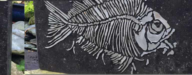 Fossil fish design hand carved into dark slate