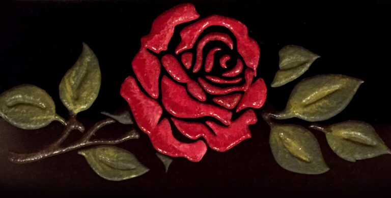 Hand-carved red rose with gilded leaves on a black slate plaque