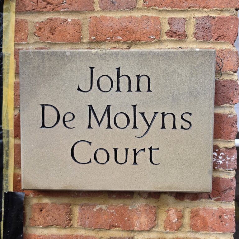 Engraved house name sign set into a brick wall
