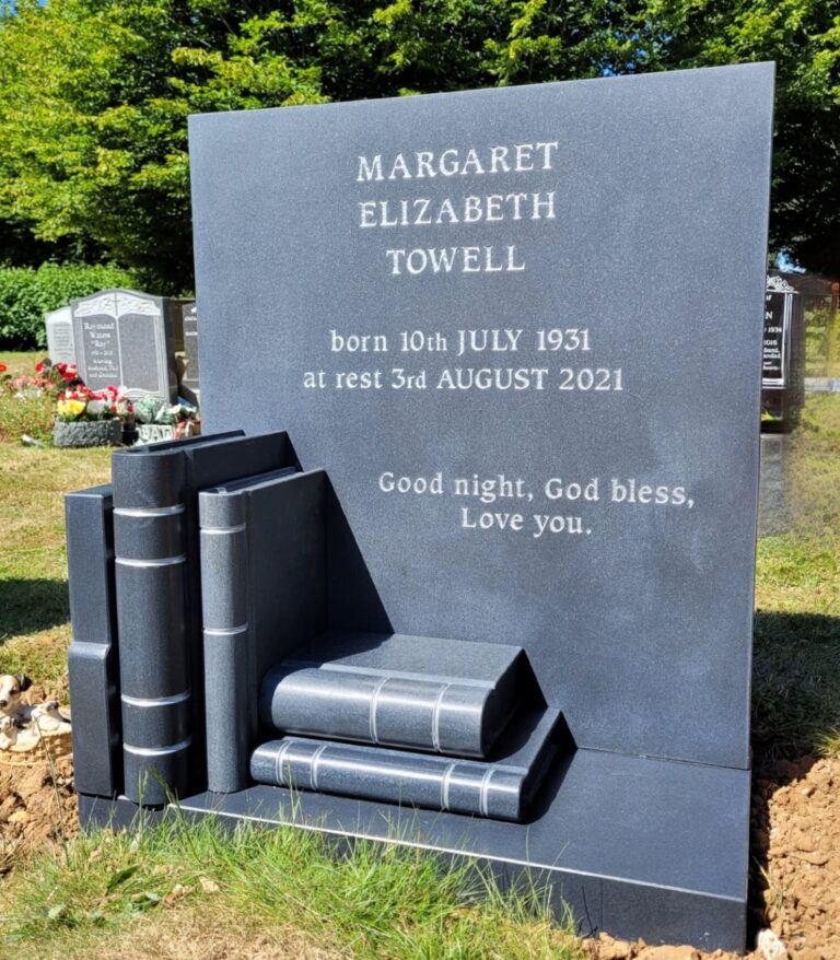 Grey granite headstone with carved books