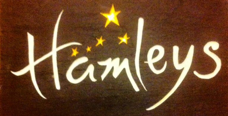 Carved Hamleys sign with gold lettering and stars on dark stone