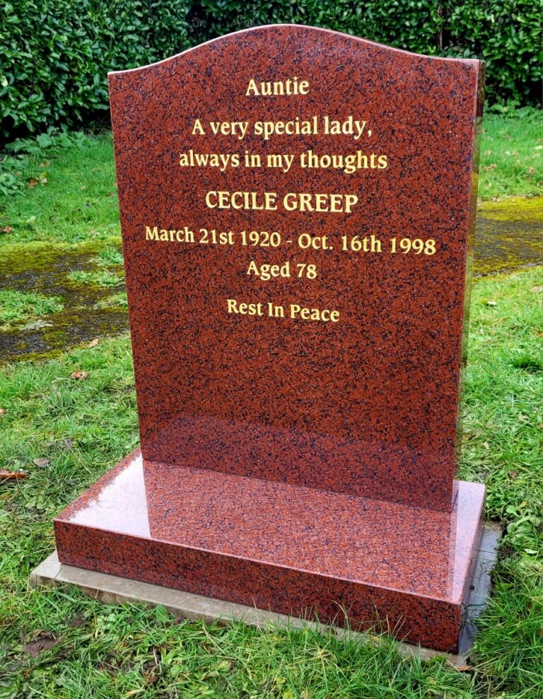 Red granite headstone with gold lettering in a lawn cemetery
