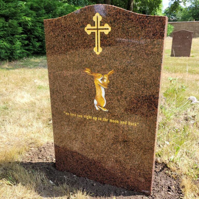 Red granite headstone with a gilded cross and gold motif