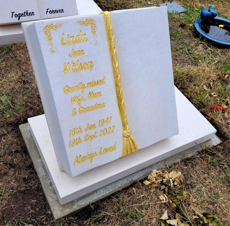 White marble headstone with a gold leaf design